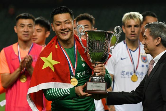 Shandong Luneng's Wang Dalei celebrates with the trophy after his team won the final of the Lunar New Year Cup football tournament in Hong Kong