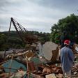 People look at a firefighter helicopter flying over the mud-hit area a day after the collapse of a dam at an iron-ore mine belonging to Brazil's giant mining company Vale near the town of Brumadinho, Brazil on January 26, 2019