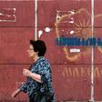 A woman passes a graffiti-strewn map in Skopje as Greek lawmakers prepare to ratify a name change for the former constituent part of Macedonia, the issue having plagued relations between the neighbours for decades