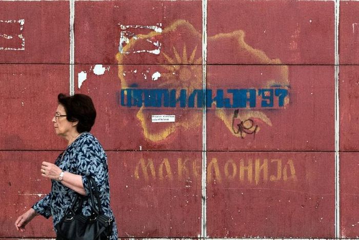 A woman passes a graffiti-strewn map in Skopje as Greek lawmakers prepare to ratify a name change for the former constituent part of Macedonia, the issue having plagued relations between the neighbours for decades
