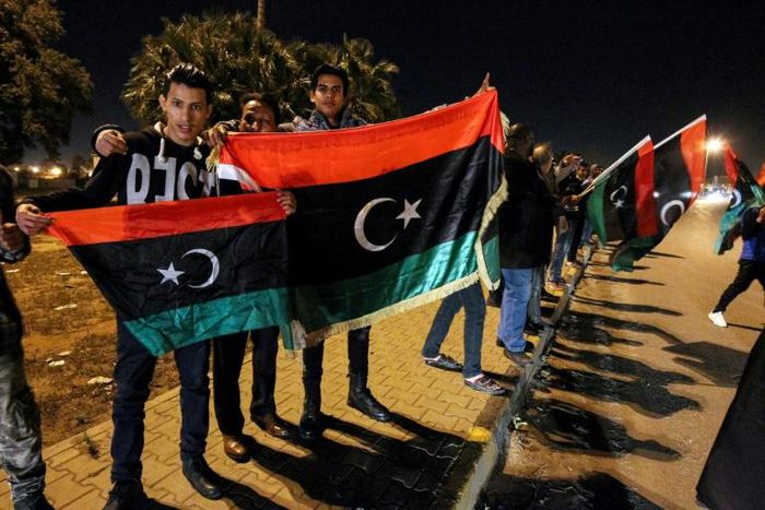 Libyans hold their national flags during a celebration marking the seventh anniversary of the revolution which toppled and killed veteran strongman Moamer Kadhafi in the eastern city of Benghazi on February 17, 2018
