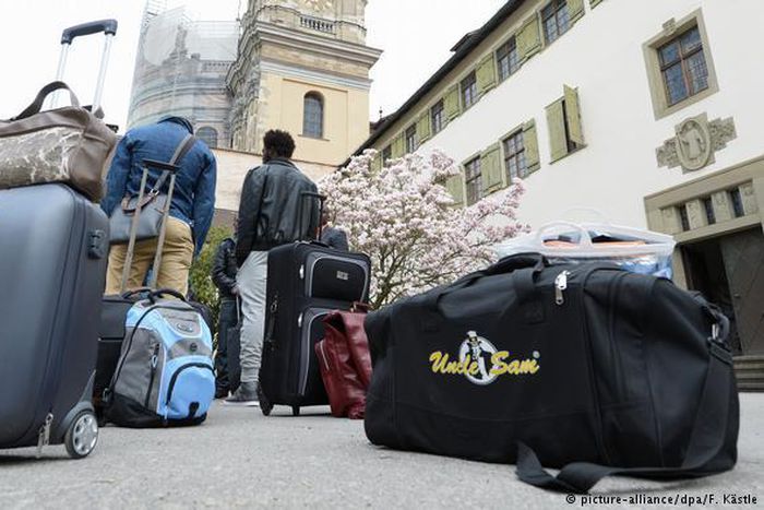 Two African migrants wait with their luggage in front of a German guesthouse Alliance/DPA/F. Kastle