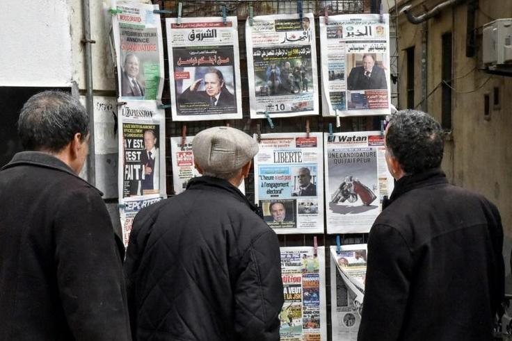 Algerians look at the headlines of newspapers at a kiosk in the capital Algiers on February 11, 2019