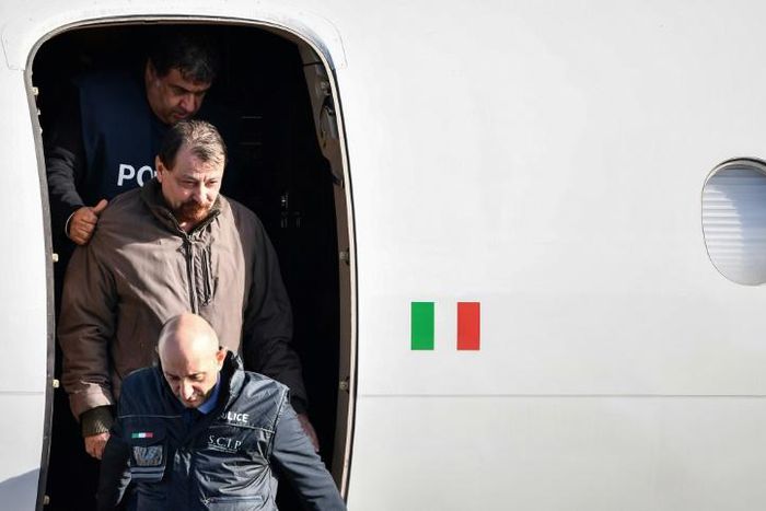 An Italian-flagged Falcon 900 plane carrying Battisti landed at Rome's Ciampino airport on Monday morning. Battisti, who was not wearing handcuffs, smiled grimly as he was escorted off the plane by a dozen police