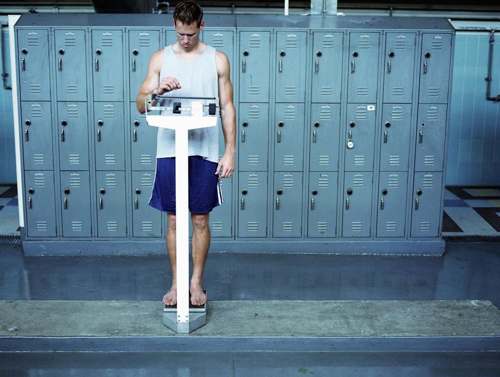 Young man stading on scale in locker room