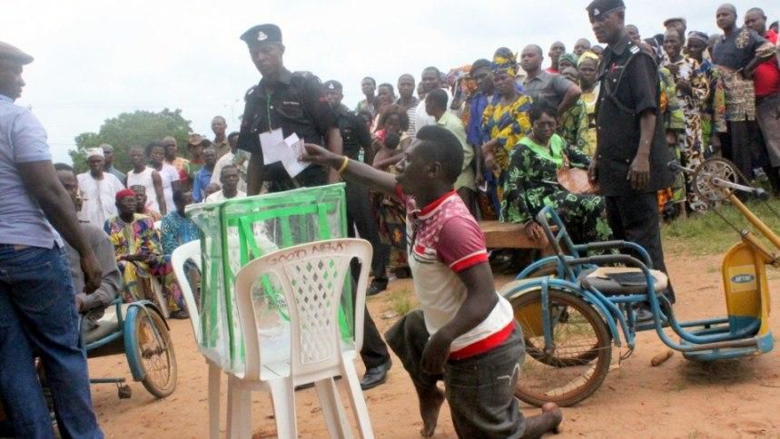 A physically challenged person casts vote in a ballot box.