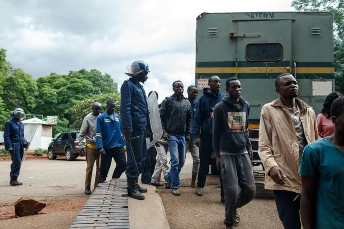 Zimbabwean anti-riot police forces watch men arrested during violent protests triggered by a sudden rise in fuel prices announced by Zimbabwean president, before their hearing at the Law Court in Harare on January 16, 2019