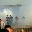 Palestinian protesters run through tear gas fumes during clashes with Israeli forces during a demonstration along the border with Israel east of Gaza City on January 11, 2019