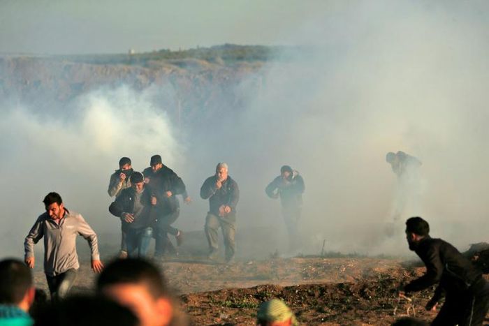 Palestinian protesters run through tear gas fumes during clashes with Israeli forces during a demonstration along the border with Israel east of Gaza City on January 11, 2019