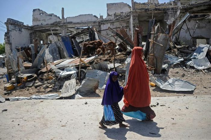 Local residents walk past the scene of a deadly December 22, 2018 car bomb attack in the Somali capital Mogadishu claimed by the jihadist group Shabaab
