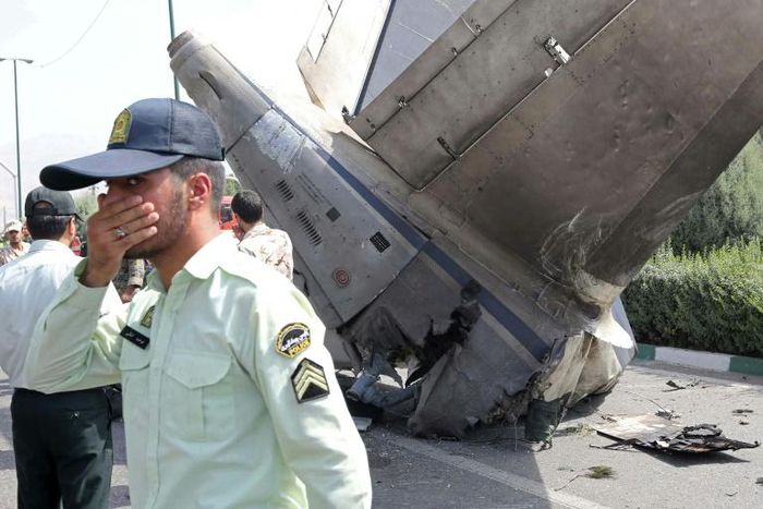 Iranian security forces stand at the scene of a previous plane crash near Tehran's Mehrabad airport on August 10, 2014