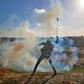 A Palestinian uses a slingshot to throw tear gas towards Israeli forces during a demonstration along the Gaza border on January 18, 2019