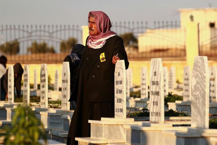 A man in the northern Syrian town of Kobane walks in a graveyard during the funeral of a fighter of the Syrian Democratic Forces killed in an offensive by the Islamic State movement