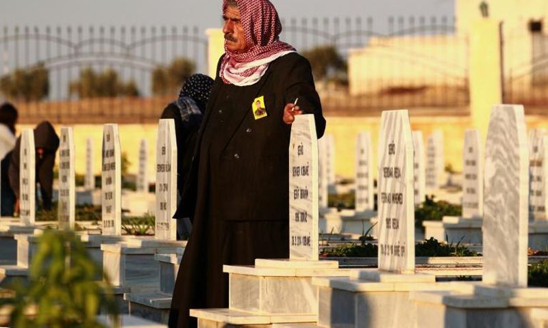 A man in the northern Syrian town of Kobane walks in a graveyard during the funeral of a fighter of the Syrian Democratic Forces killed in an offensive by the Islamic State movement