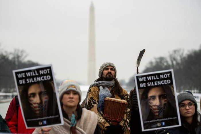 Activists hold up signs as they listen to speakers during the Indigenous People's March on the National Mall in Washington, DC,