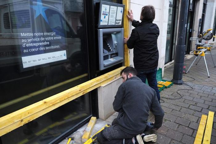 Workers installed wooden planks to protect the windows and ATM of a bank on Friday in Bourges, central France, where many "yellow vest" protesters plan to meet Saturday