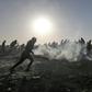 Palestinian protesters run through tear gas during clashes with Israeli forces following a demonstration at the border of the Gaza Strip on January 11, 2019