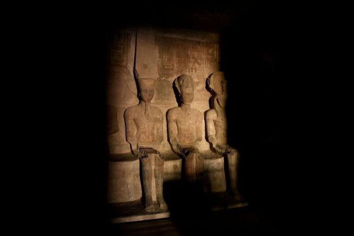 A picture taken on October 22, 2016, shows a ray of light illuminating the statue of Ramses II inside the temple of Abu Simbel in Egypt