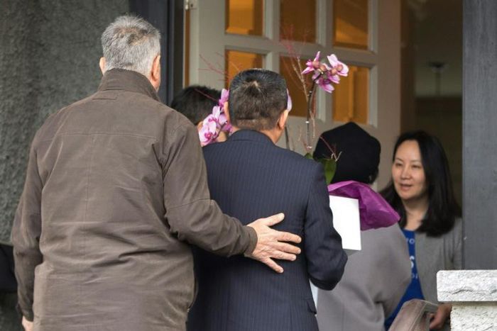 (FILES) In this file photo taken on December 12, 2018 Meng Wanzhou (R), Chief Financial Officer of Huawei Technologies, answers the door for individuals carrying flowers after she was released on bail in Vancouver, British Columbia on December 12, 2018...