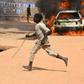 A boy runs off as cars are set on fire in Kofa