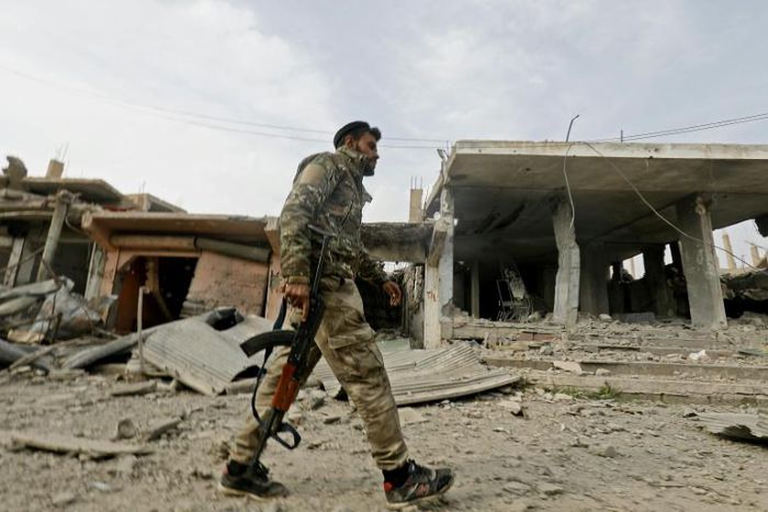 A fighter from the Syrian Democratic Forces (SDF) walks through the town of Hajin after it was recaptured from the Islamic State (IS) group