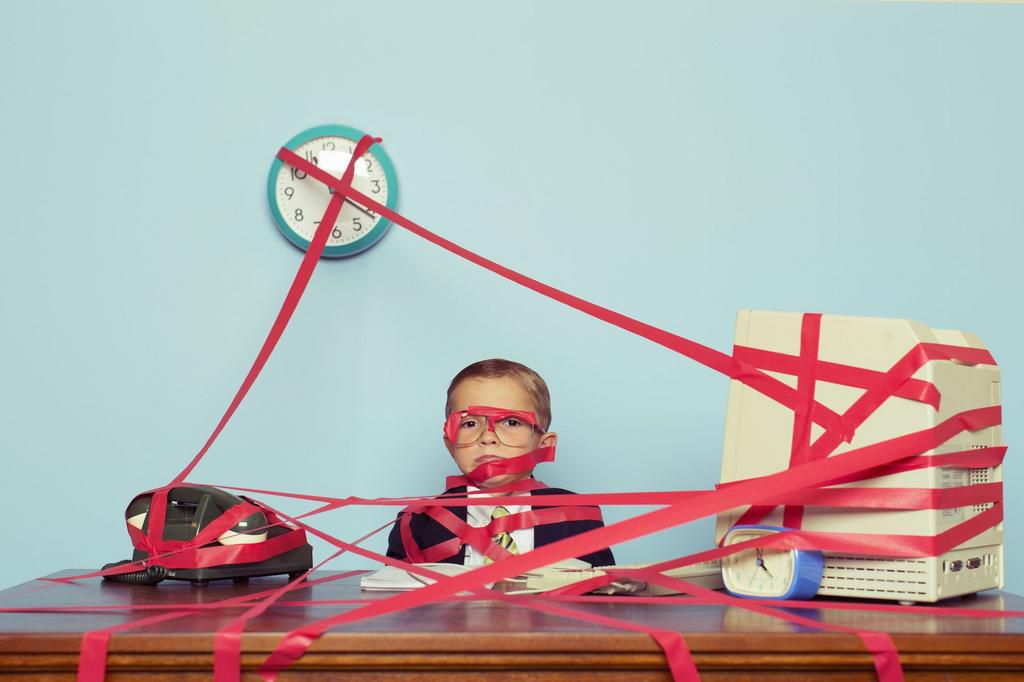 Young Boy in Business Office is Covered in Red Tape