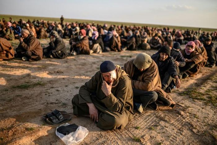 Suspected Islamic State group fighters wait to be searched after leaving the jihadists' last holdout in eastern Syria