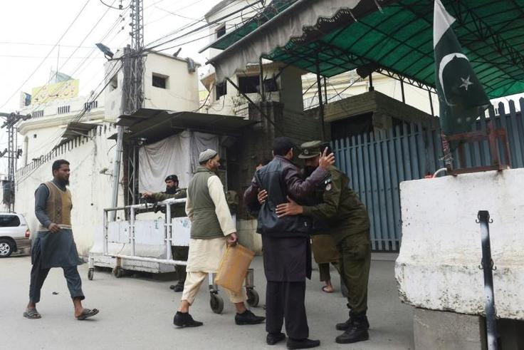 A Pakistani police officer frisks worshippers as they arrive for Friday prayers before entering a mosque of banned militant group Jamaat-ud-Dawa