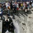 People collect water from a broken pipe flowing into a sewage canal at the Guaire river in Caracas on March 11, 2019