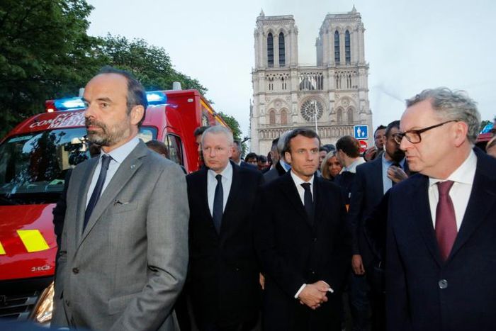 French Prime Minister Edouard Philippe (L), and French President Emmanuel Macron (3rd L) gather near the entrance of the Notre-Dame Cathedral in Paris, as flames engulf its roof