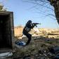 A fighter with the Syrian Democratic Forces (SDF) takes aim with his Kalashnikov assault rifle after seeing a man walking towards his position in the town of Baghouz, in the eastern Syrian province of Deir Ezzor, on March 9, 2019