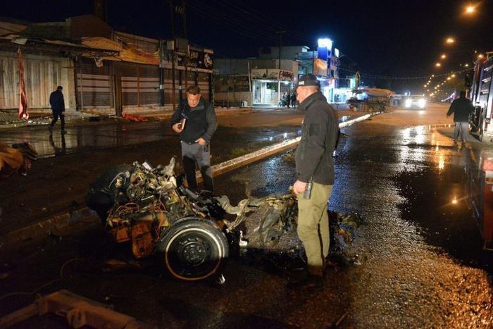 Iraqi security forces inspect the scene of the car bomb attack outside a restaurant in Iraq's Mosul