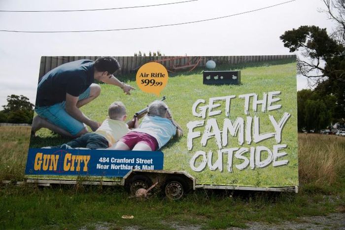 Anger has focussed on Gun City's billboard on a busy highway showing a man teaching two children how to shoot