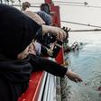 Iraqi women throw flowers into the Tigris River as they mourn 100 people killed in a ferry capsize