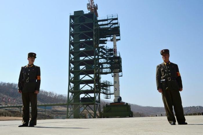 Two North Korean soldiers stand guard in front of the Unha-3 rocket at at the Sohae Satellite Launch Station
