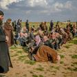 A man prays as men suspected of being Islamic State (IS) fighters wait to be searched by members of the Kurdish-led Syrian Democratic Forces (SDF) in Syria's northern Deir Ezzor province, on February 22, 2019