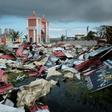 People collect metal sheets from a damaged supermarket to rebuild their houses destroyed by Cyclone Idai in Beira, Mozambique