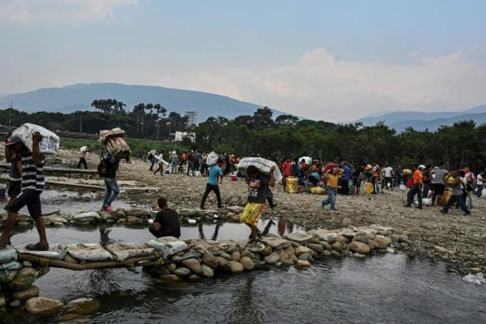 People carry goods along the "trochas" -illegal trails on the border between Cucuta in Colombia and San Antonio del Tachira in Venezuela, on April 13, 2019
