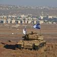 An Israeli flag flutters over the wreckage of an Israeli tank overlooking the armistice line on the Golan Heights
