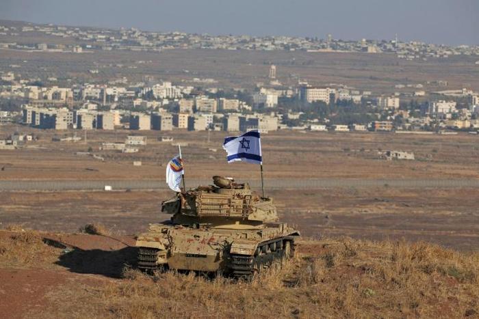 An Israeli flag flutters over the wreckage of an Israeli tank overlooking the armistice line on the Golan Heights