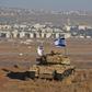 An Israeli flag flutters over the wreckage of an Israeli tank overlooking the armistice line on the Golan Heights