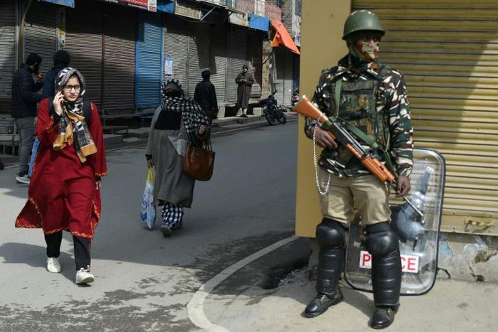 An Indian paramilitary trooper stands guard in front of closed shops in Srinagar in March