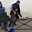 Algerian security forces drag a man away as they respond to protests in the capital Algiers on Friday