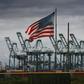 The US flag flies over shipping cranes and containers in Long Beach, California, where a lot of Chinese exports land