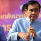 Thailand's Prime Minister Prayut Chan-O-Cha plays with a traditional flute as he arrives at the government house for a cabinet meeting on Tuesday, two days after the country's general election