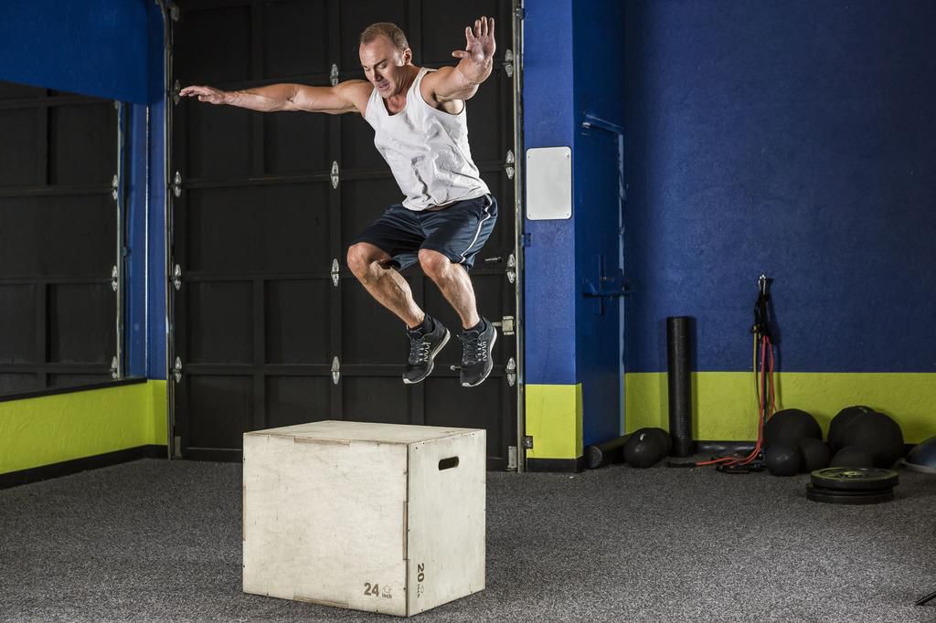 Man performing box jump in gym