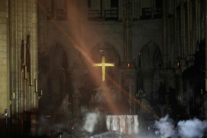 Smoke rises around the alter in front of the cross inside the Notre-Dame Cathedral in Paris as firefighters continued to extinguish the blaze on Tuesday