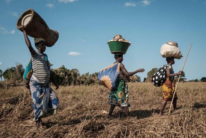 Evacuated women walked to a shelter after collecting maize on the ground which was under flooded water because of Cyclone Idai