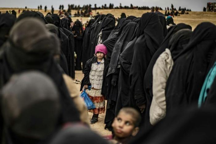 Women and children queue at a screening point after fleeing the Islamic State group's last redoubt in Syria