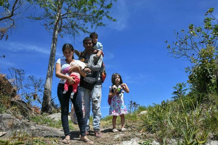 Venezuelan policeman Cesar Marcano with his wife Adriana Ballera and their children, using a mountain trail to cross into Brazil